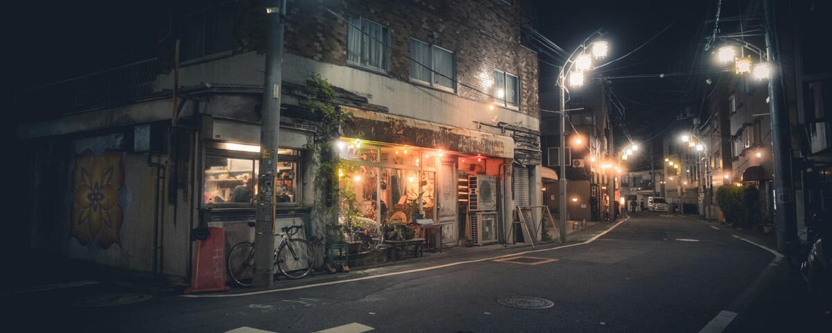 A dark street corner lit only by shop windows late at night