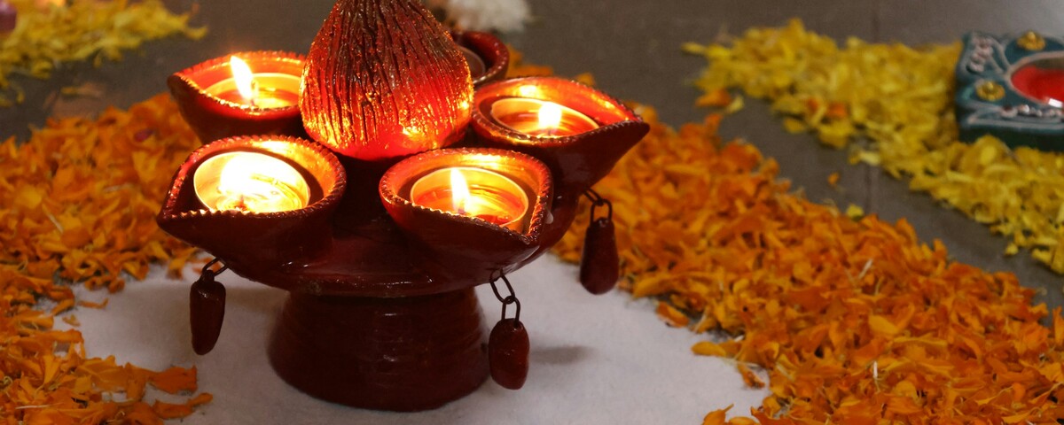 Lit clay diyas arranged around a flower rangoli for Diwali