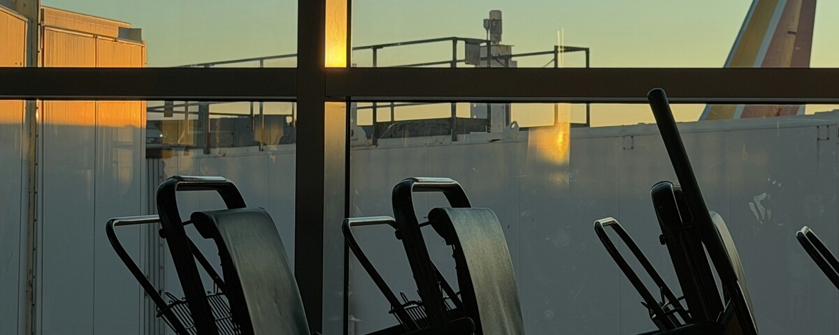 Empty airport gate seating in silhouette against a low evening sun