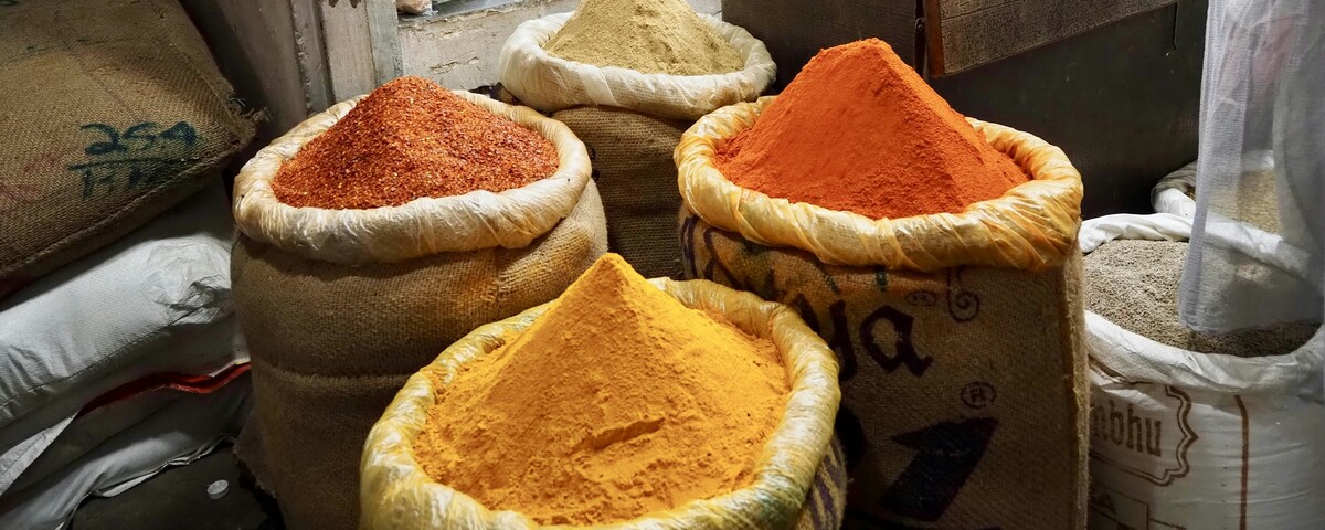 Sacks of turmeric, chilli and ground spice open on the floor of a grocery
