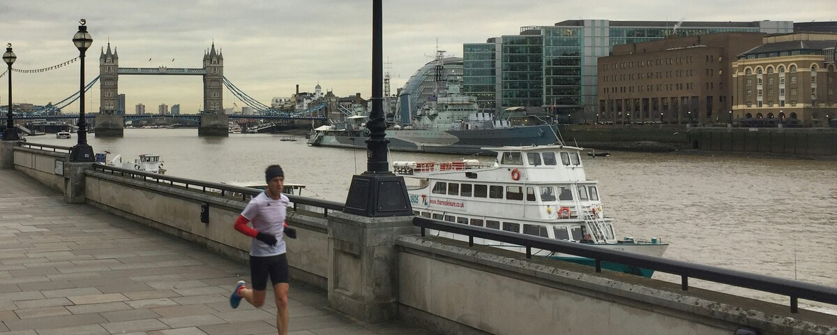 A runner on the Thames path with Tower Bridge behind