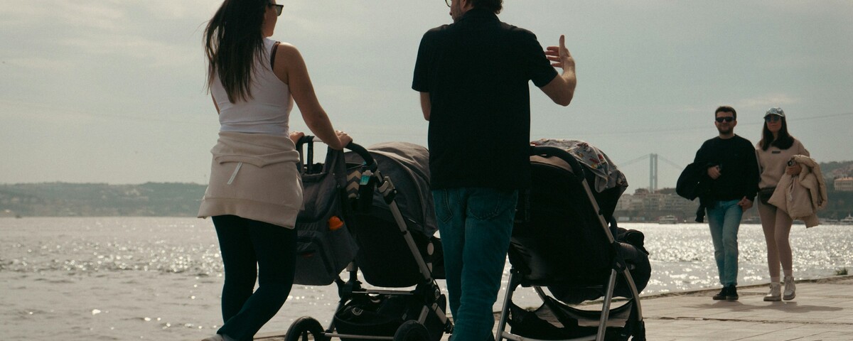 Two people pushing buggies side by side along a waterfront path