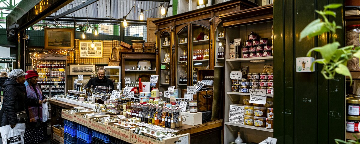 A produce and preserves stall under the iron roof of Borough Market