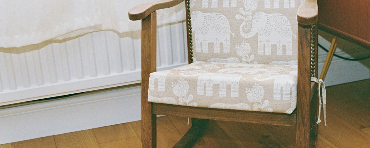 A wooden nursing chair beside a radiator in soft daylight