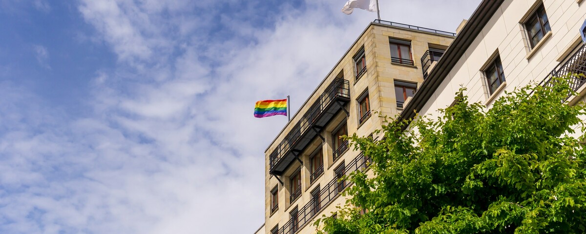 A rainbow flag flying from the front of a building in daylight