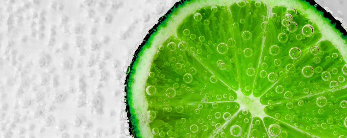 A wedge of lime in a tall glass of sparkling lemonade