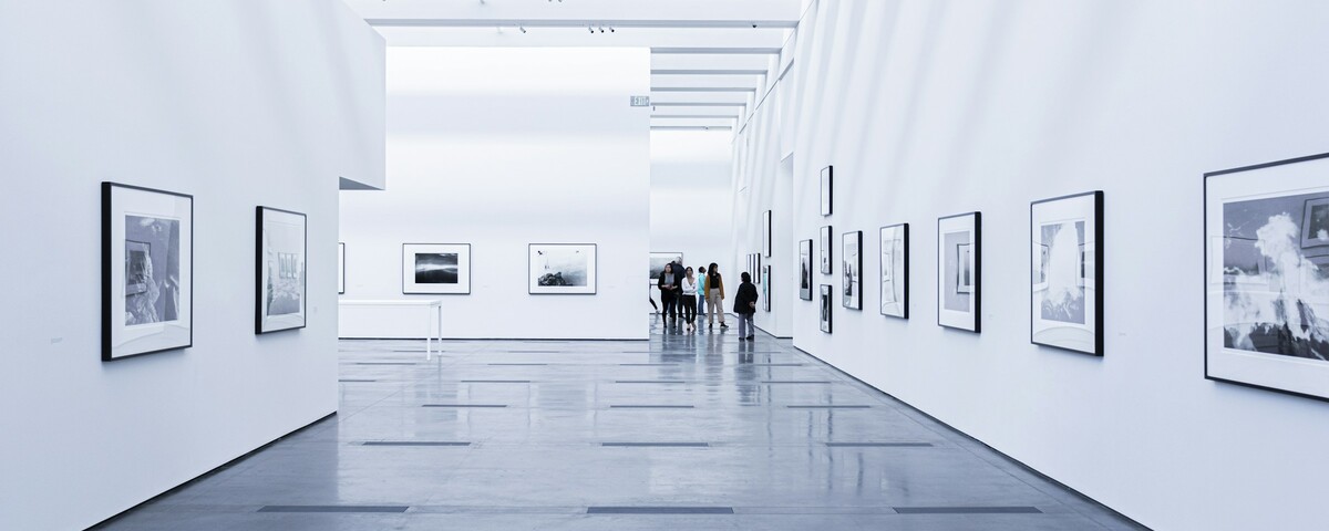 A bright, near-empty gallery room hung with paintings